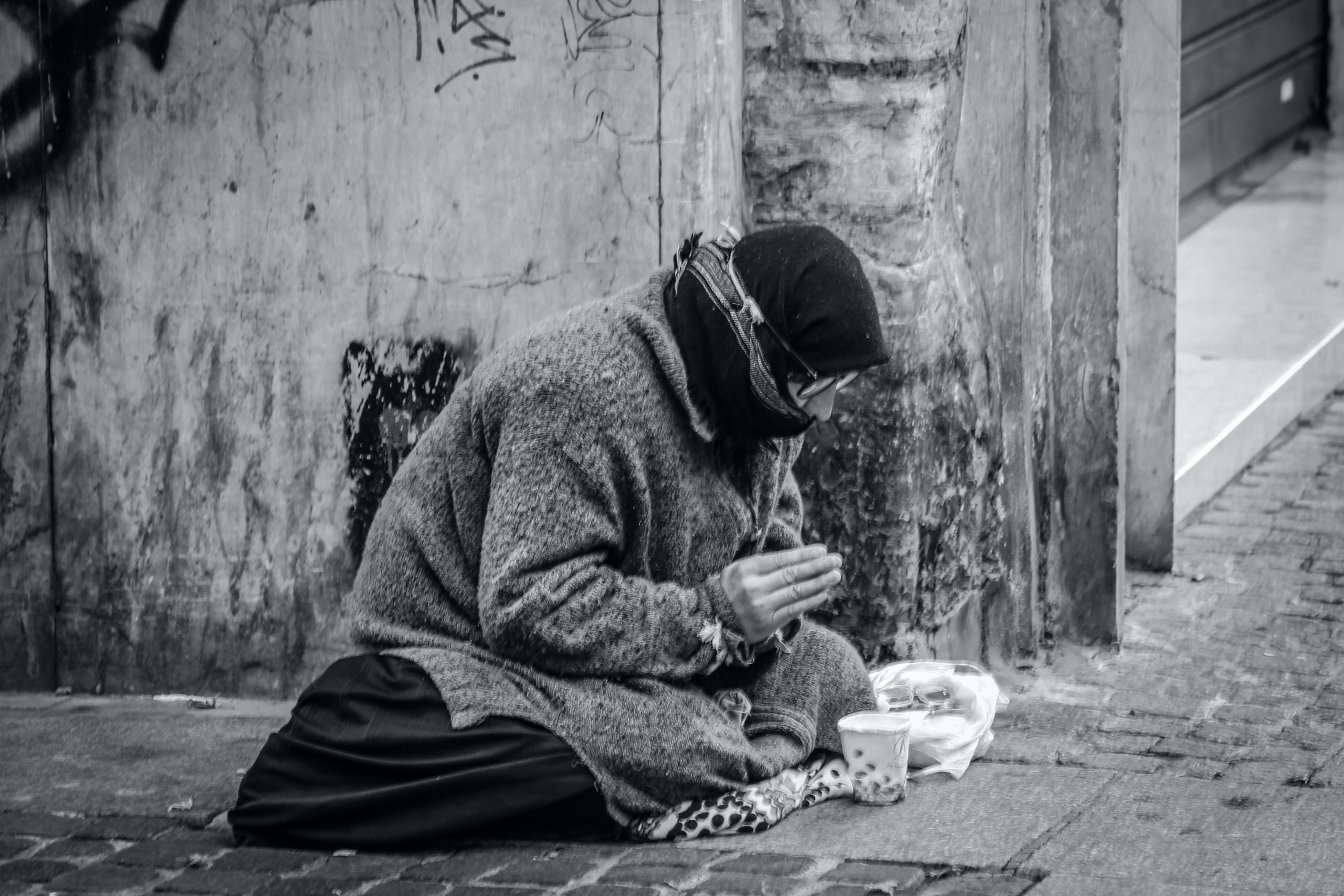 homeless man in the street eating out of a container while attempting to recover from drug addiction