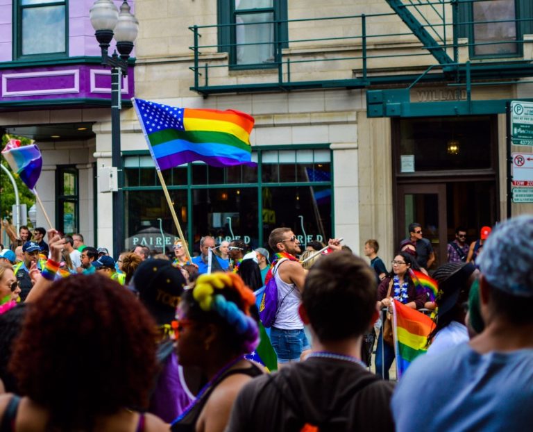people waving the lgbtq flag in the street during a parade for awareness of substance abuse in the lgbtq community