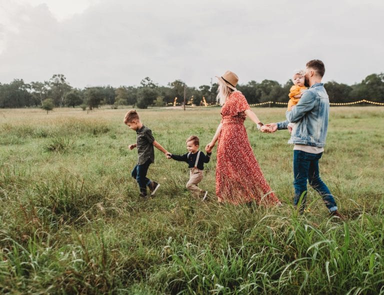 happy family of five walking through a meadow to symbolize how addiction affects the family