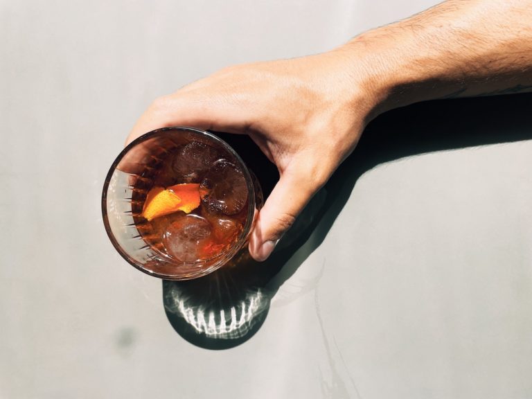 hand reaching for an alcoholic drink to symbolize the dangers of binge drinking