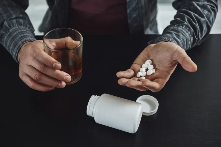 person holding a drink and pills