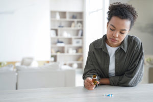 pensive young girl holding jar of pills