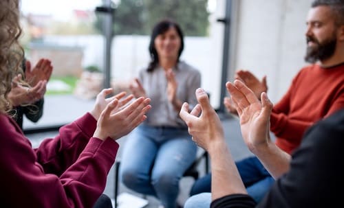 people sitting in a circle clapping hands during a 12 step meeting