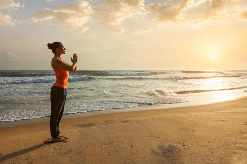 woman doing yoga on the beach for holistic addiction treatment