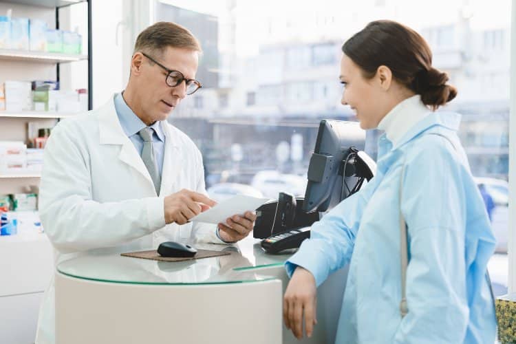 Pharmacist looking at prescription dispensing medications to customer