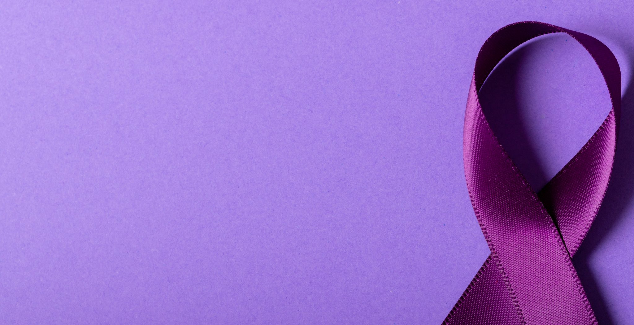 Directly above shot of purple awareness ribbon isolated against purple background, copy space. epilepsy, pancreatic cancer, medical, awareness, ribbon, support, healthcare and alertness concept.