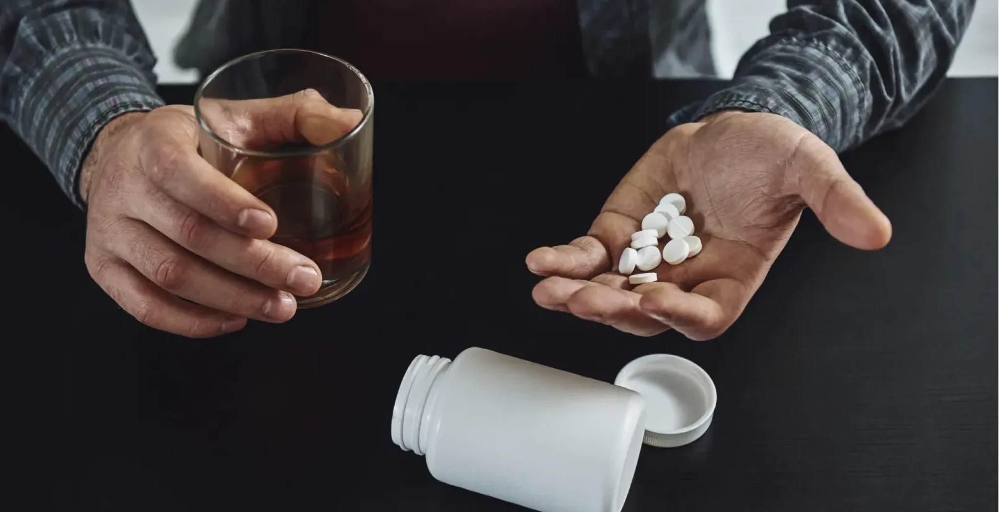 person holding a drink and pills