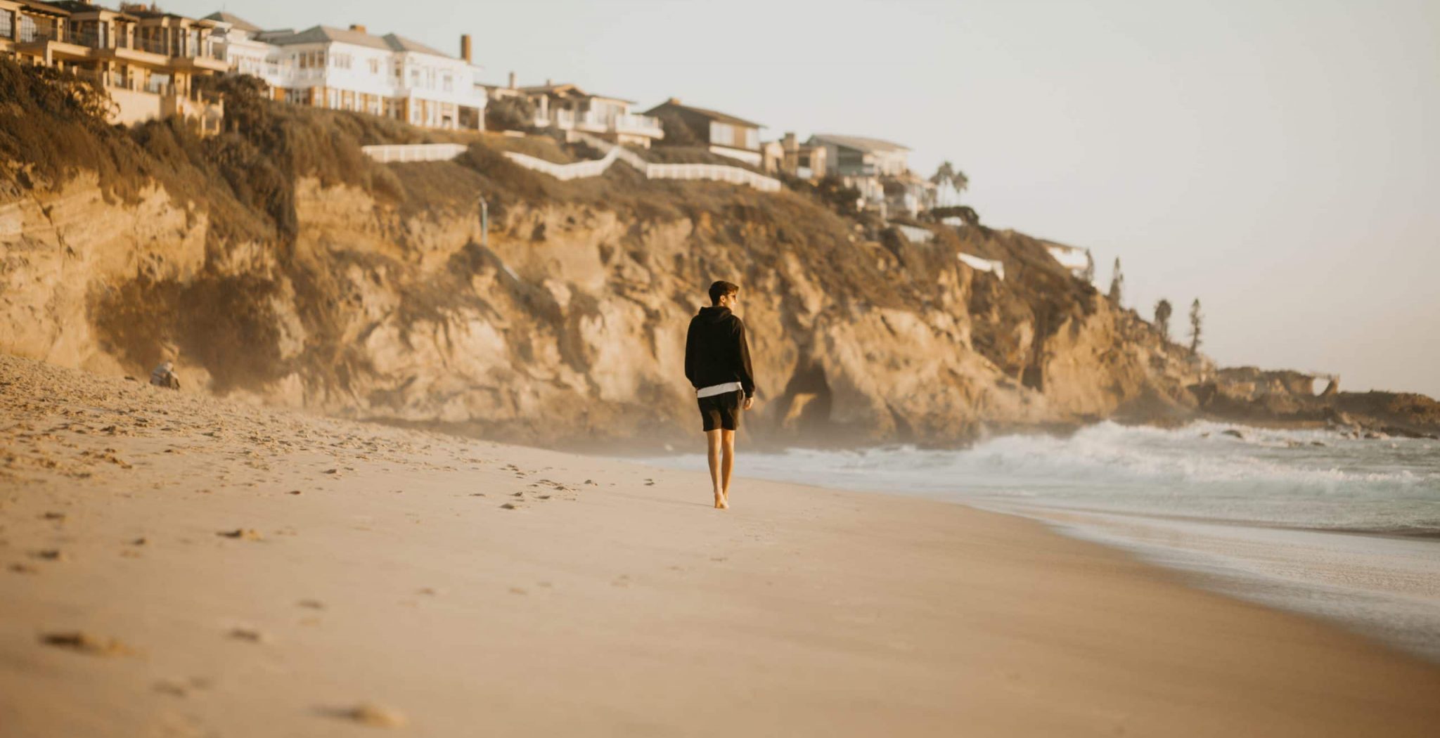 person walking along the beach near an addiction therapy center in Orange County California