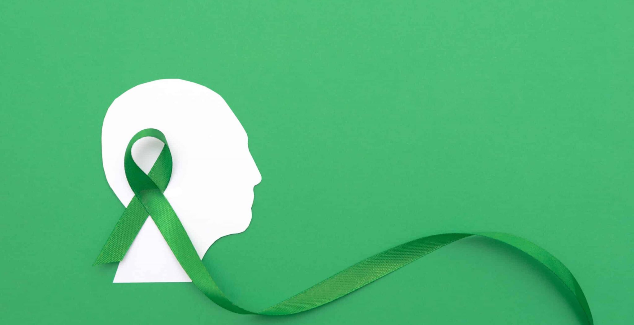 Silhouette of a Human Head with large Green Ribbon on Green Background Representing Mental Health Awareness