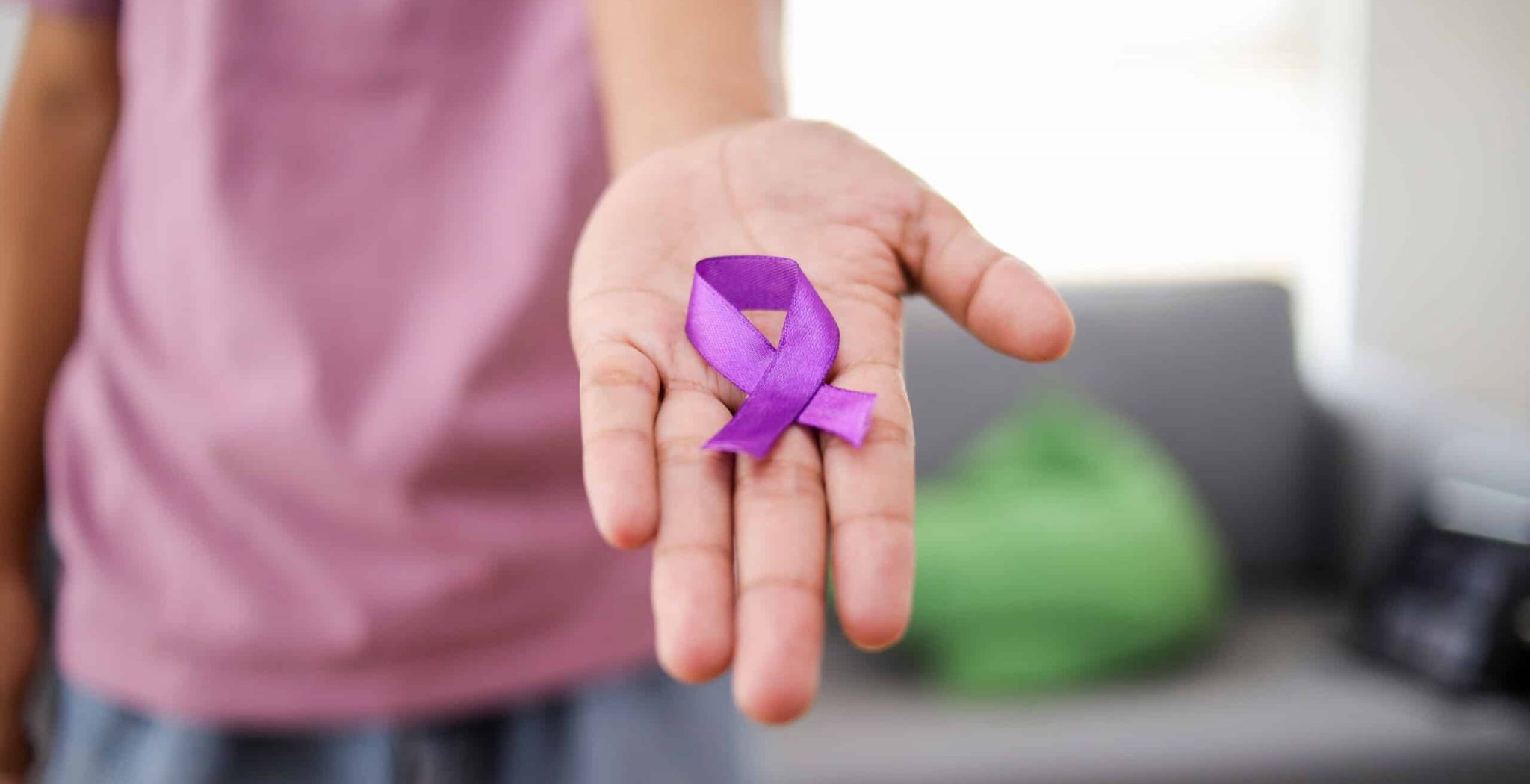 World Cancer Day. Man Hand Holds Purple Ribbon at Home.