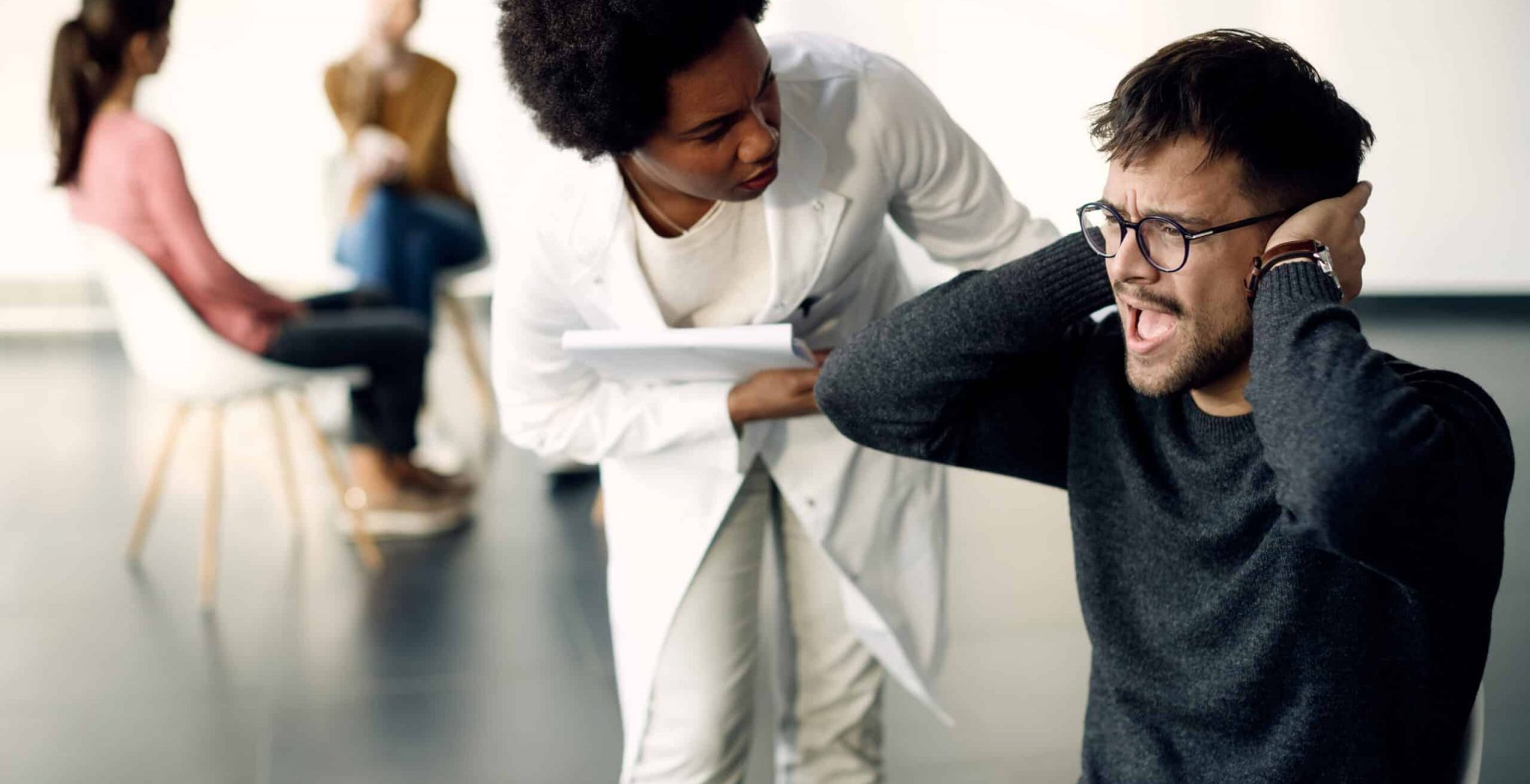 Anxious man covering his ears and screaming while psychotherapist is trying to talking to his during group therapy. Oppositional Defiant Disorder vs. Conduct Disorder.